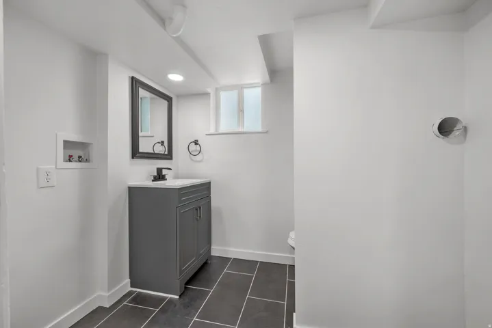 Bathroom featuring a dark gray vanity with a white countertop, matte black faucet, and coordinating framed mirror