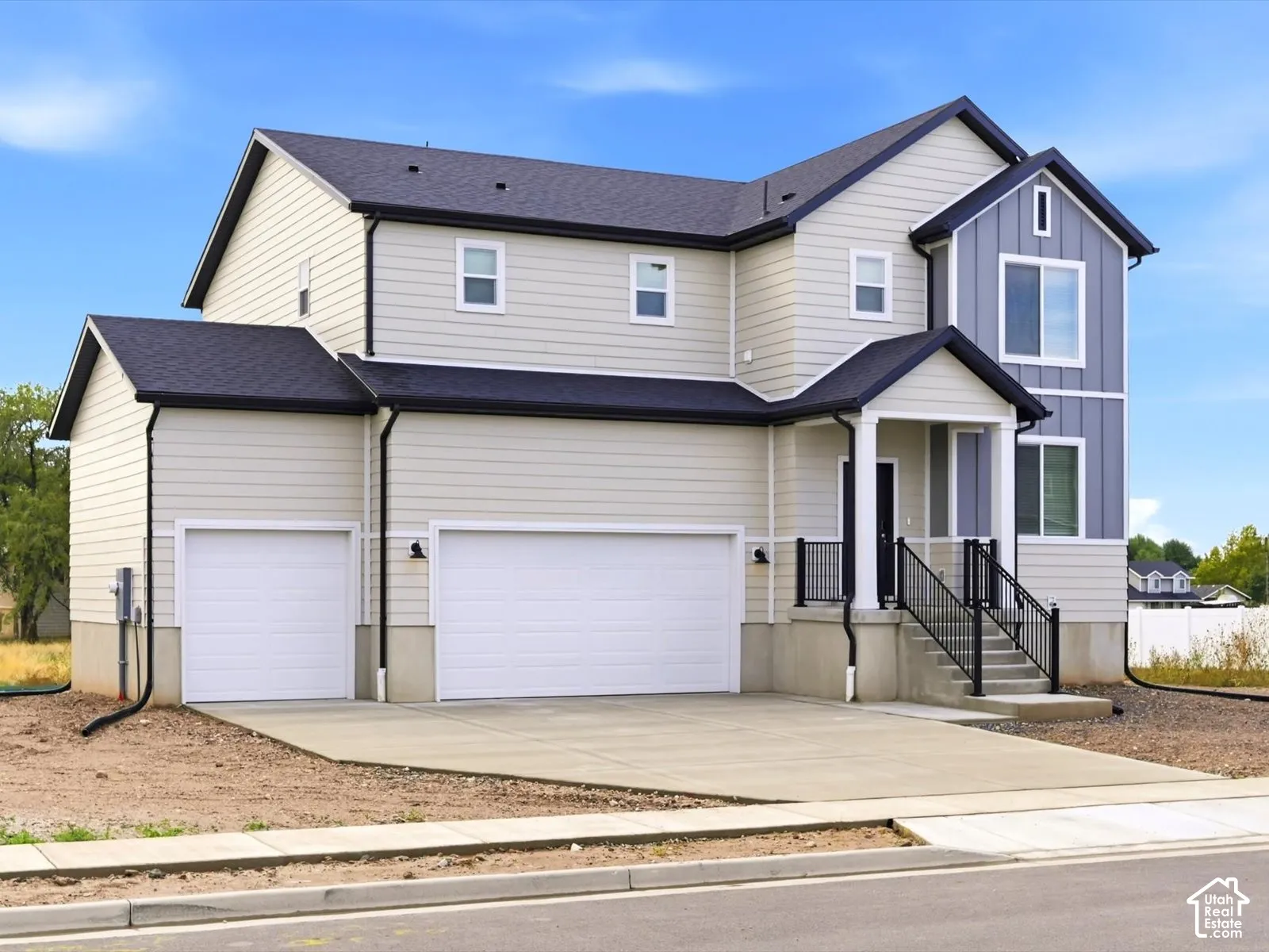 Multi-level exterior featuring horizontal lap siding, vertical board-and-batten accents, a covered front entryway, three-car garage, and concrete driveway