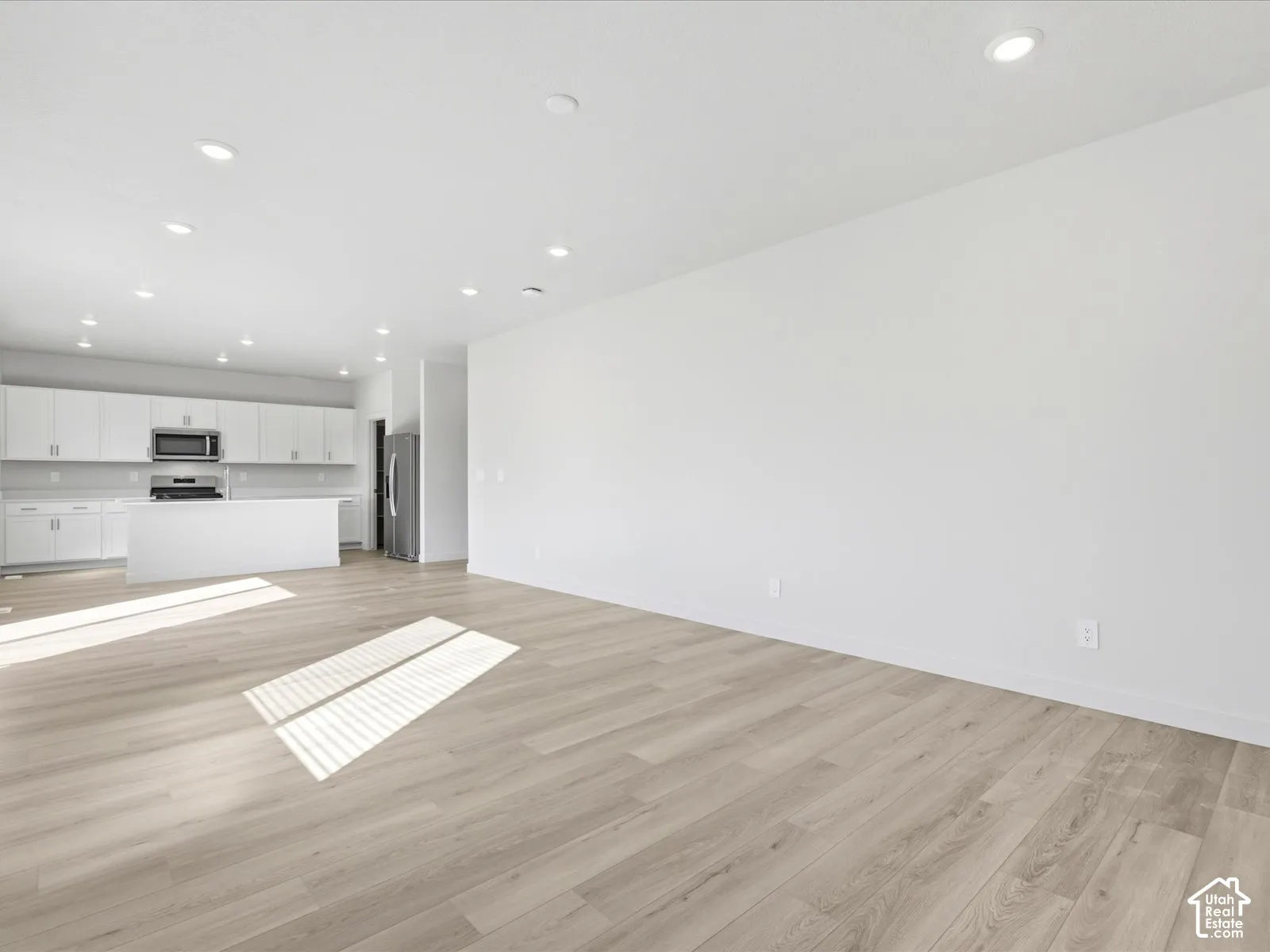 Open-concept space featuring wood-finish flooring, recessed lighting, white cabinetry, and a kitchen island