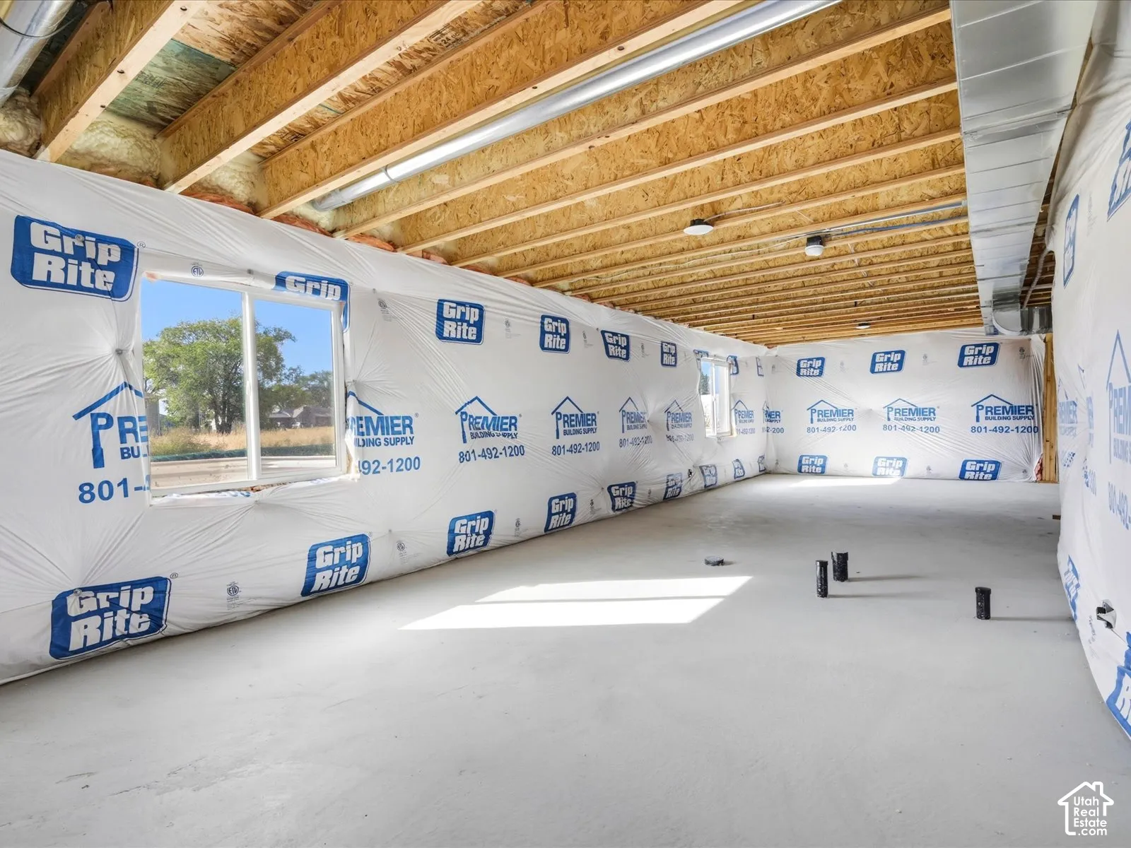 Unfinished basement featuring exposed wood ceiling joists, concrete flooring, and multiple double-pane windows