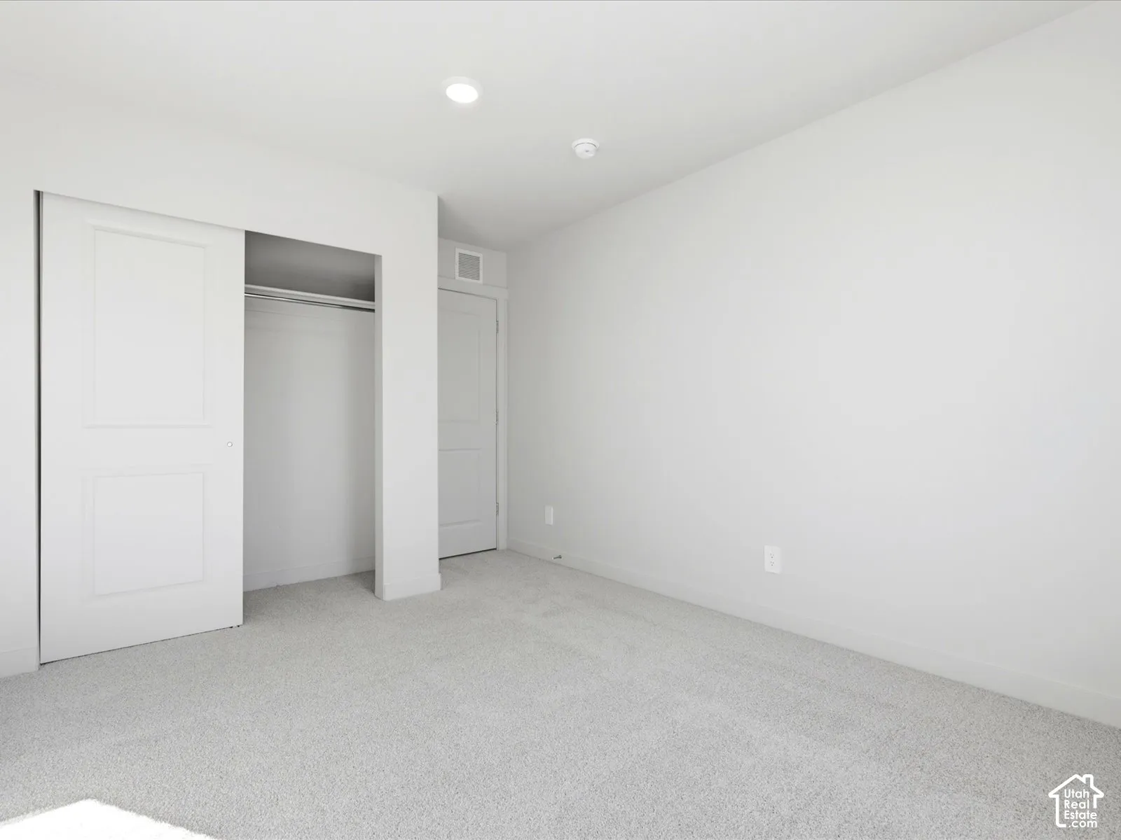 Neutral-toned interior featuring wall-to-wall carpeting, recessed ceiling lighting, and a closet with a two-panel sliding door