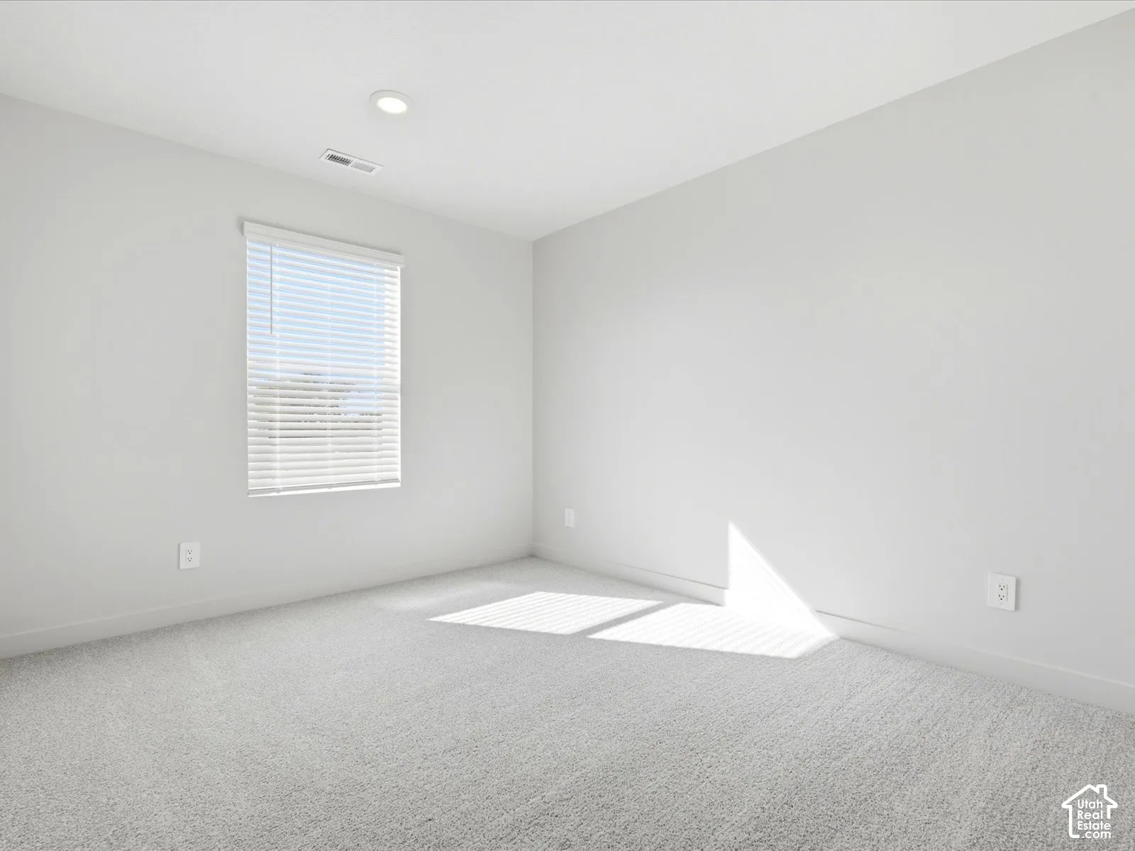 Neutral interior featuring wall-to-wall carpeting, recessed ceiling lighting, and a horizontal blind window treatment
