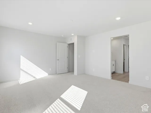 Neutral interior featuring wall-to-wall carpeting, recessed lighting, and a solid-core panel door