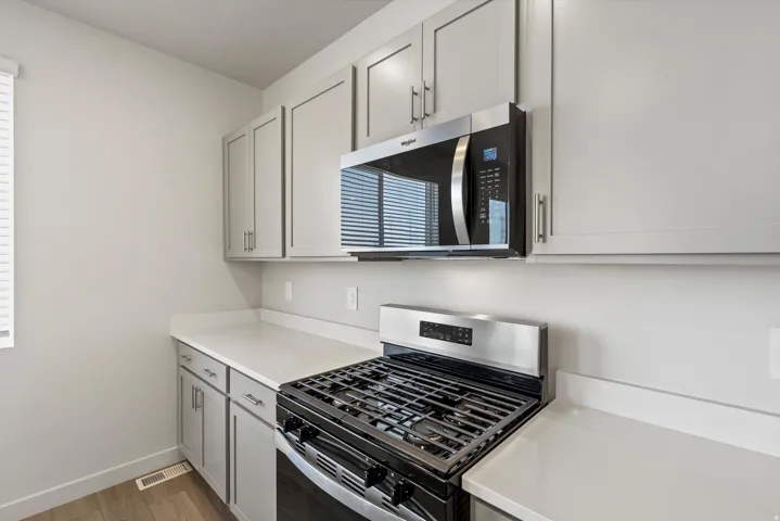 **DISCLAIMER** Interior package may vary. Stainless steel range with a built-in microwave, light gray cabinetry, light countertops, and wood-finish flooring