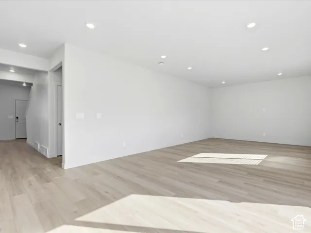 Neutral interior featuring wood-finish flooring, recessed lighting, and crisp white wall finishes
