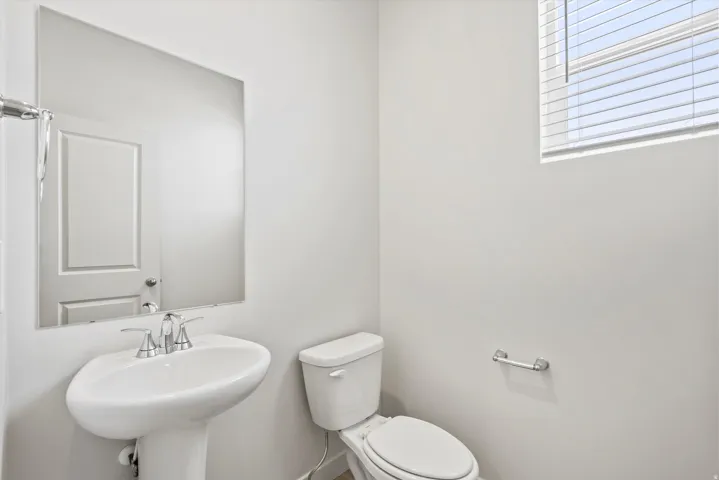 **DISCLAIMER** Interior package may vary. Pedestal sink with chrome faucet, wall-mounted mirror, and white toilet