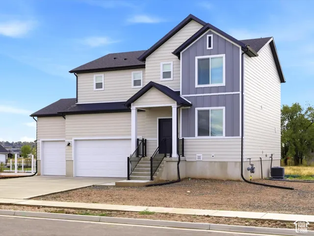 Two-story exterior featuring a mix of horizontal lap siding and vertical board-and-batten accents, a covered front entryway with metal railings, a concrete driveway, and an attached three-car garage