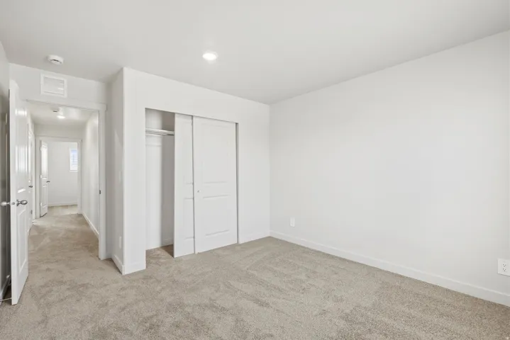 **DISCLAIMER** Interior package may vary. Spacious room featuring neutral carpeting, a large closet with sliding doors, and recessed ceiling lighting