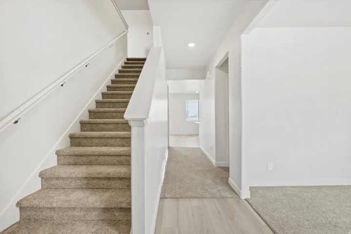 **DISCLAIMER** Interior package may vary. Carpeted staircase with white balusters and handrail, featuring a neutral color palette throughout