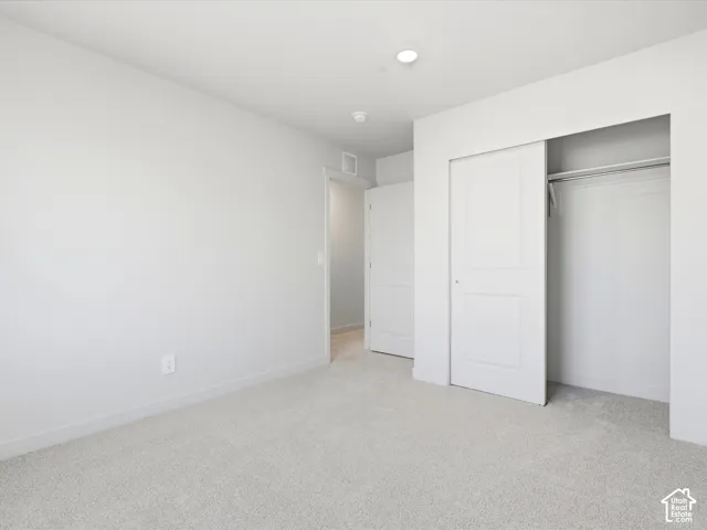 Neutral interior space featuring wall-to-wall carpeting, a sliding closet door, and a multi-panel interior door