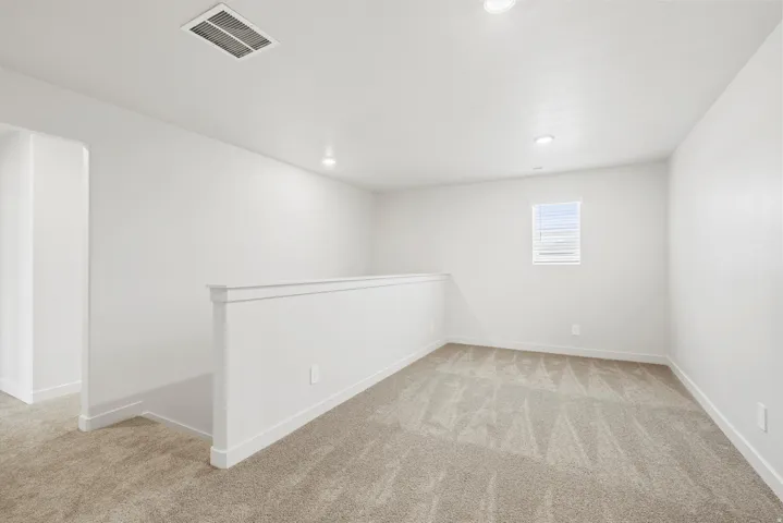 **DISCLAIMER** Interior package may vary. Carpeted loft area featuring a half-wall partition, recessed lighting, and a single window with horizontal blinds