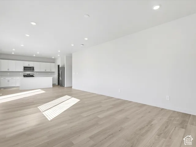 Open-concept space featuring wood-finish flooring, recessed lighting, white cabinetry, and a kitchen island