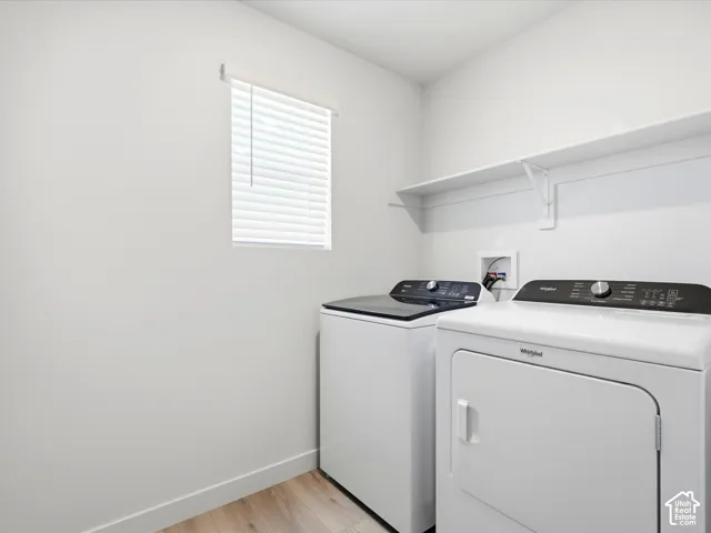 Laundry room featuring wood-finish flooring, a wall-mounted shelving unit, and a window with horizontal blinds