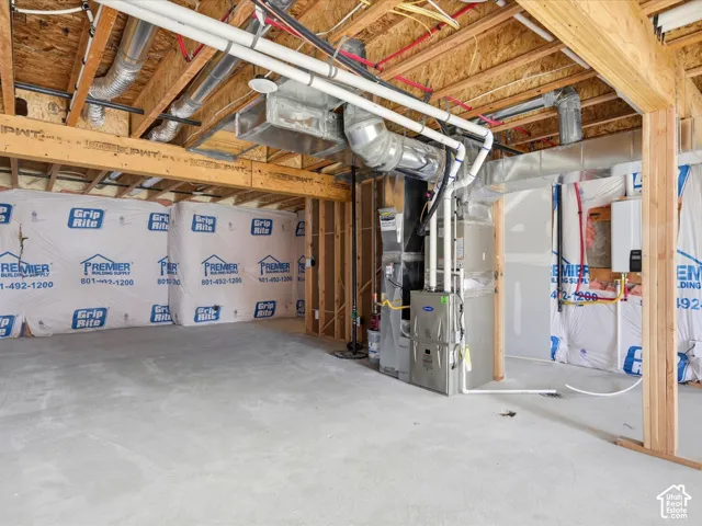 Unfinished lower level featuring exposed wood joist ceilings, concrete flooring, structural support beams, installed HVAC system, and wall-mounted tankless water heater