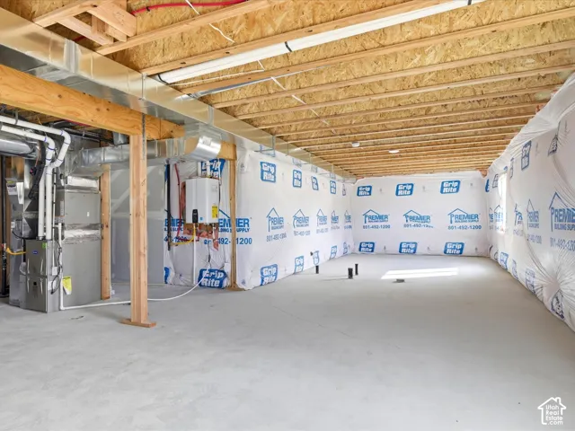 Unfinished lower level featuring exposed wood joist ceilings, concrete flooring, foundation wall vapor barriers, and installed HVAC and tankless water heating systems