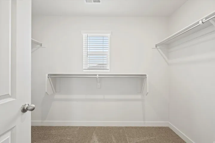 **DISCLAIMER** Interior package may vary. Walk-in closet with white walls, carpeted flooring, and a single window with horizontal blinds