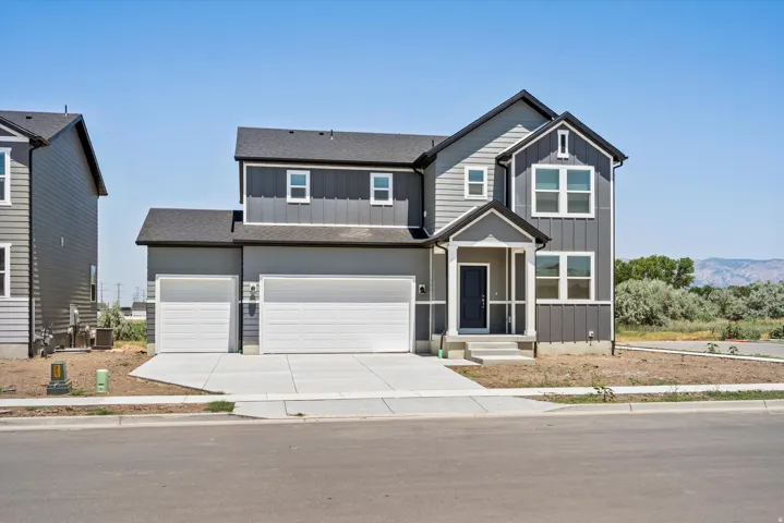 Contemporary two-story residence featuring a two-car garage, dark gray siding, and white trim accents