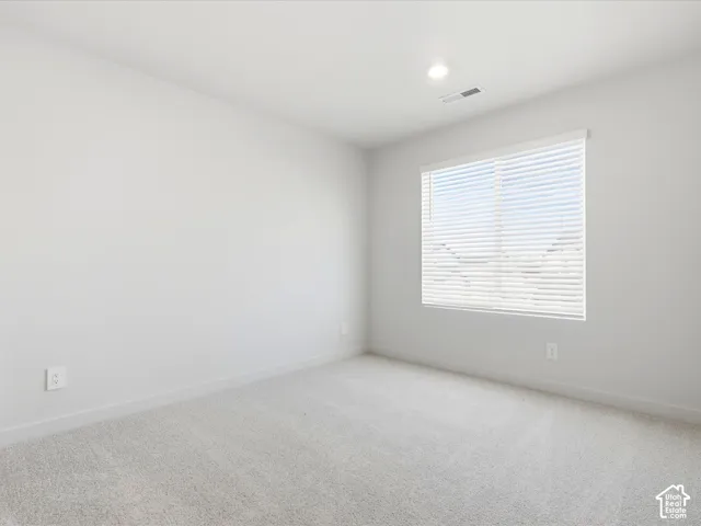 Neutral-toned wall paint, wall-to-wall carpeting, and a window with horizontal blinds