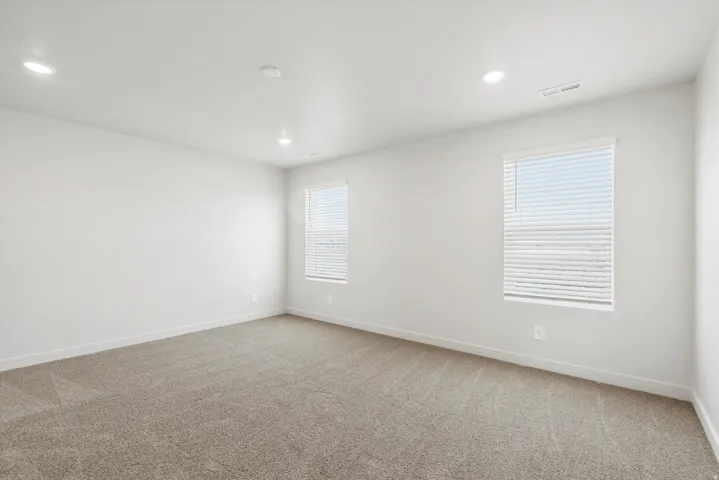 **DISCLAIMER** Interior package may vary. Spacious room featuring neutral carpeting, recessed lighting, and two windows with blinds