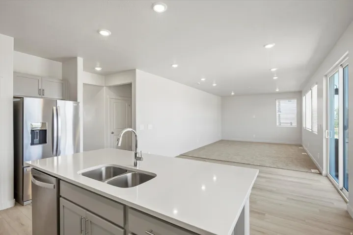 **DISCLAIMER** Interior package may vary. Kitchen island featuring a double-basin sink, gooseneck faucet, and light-toned solid surface countertop