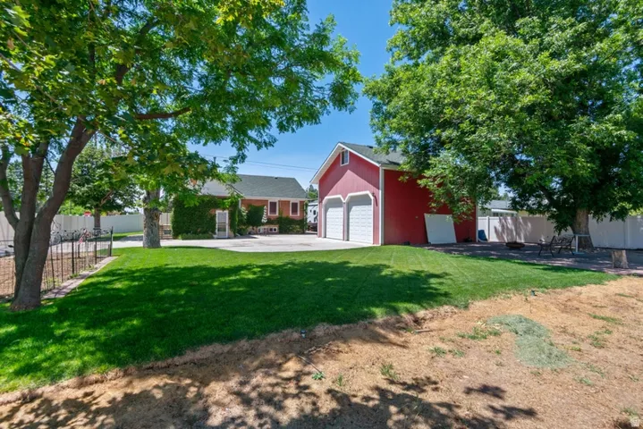 Expansive green lawn with mature trees and a detached two-car garage