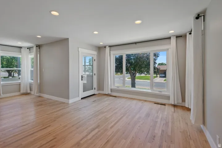 Spacious living room featuring hard wood flooring, fresh paint, recessed lighting, and new Milgard Windows
