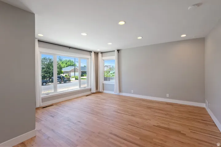 Spacious living room featuring wood-finish flooring, recessed lighting, and expansive windows