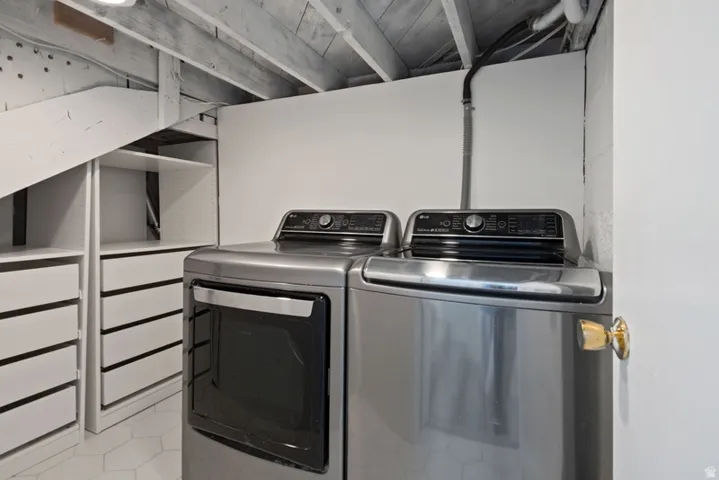 Dedicated laundry area featuring includedl washer and dryer pair with storage with drawers and shelving