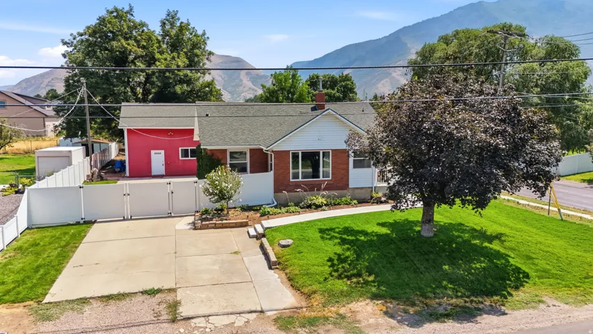 Brick and siding exterior with a red detached garage, concrete driveway, and white privacy fence