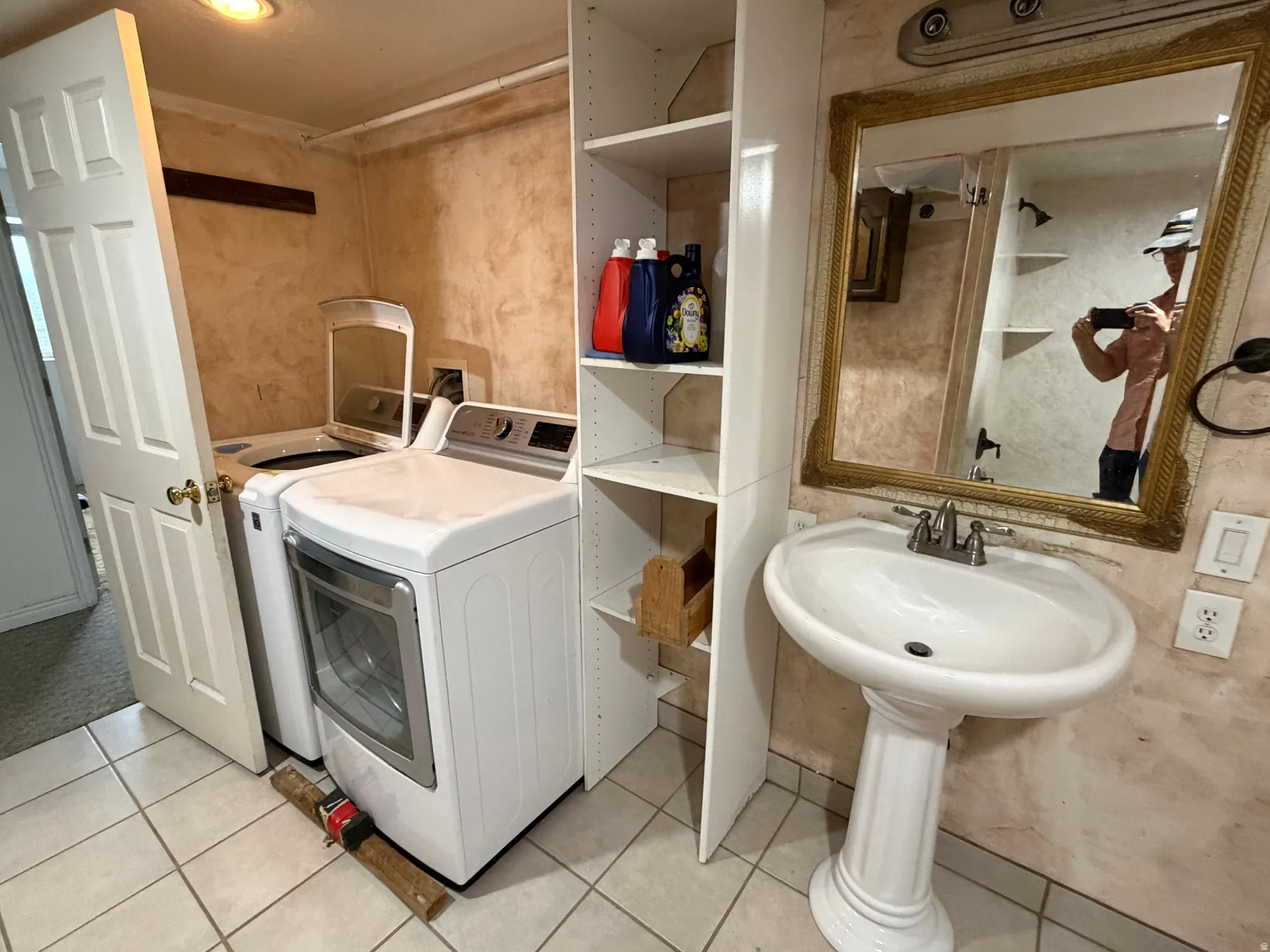 Dedicated laundry space featuring a white washer and dryer, adjacent to a pedestal sink with a framed mirror