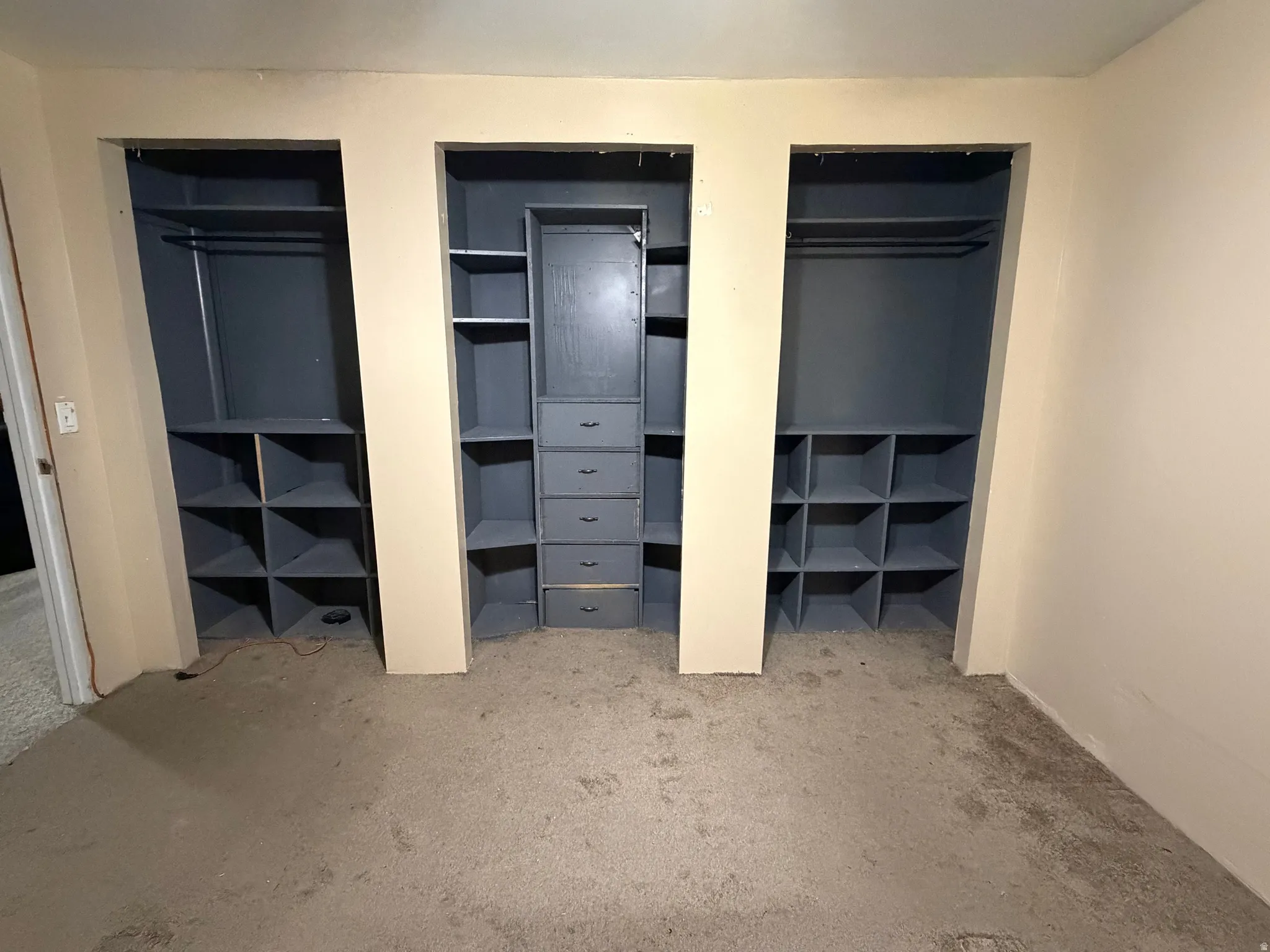 Built-in closet system featuring three bays, integrated shelving, hanging rods, and a central dresser unit with multiple drawers