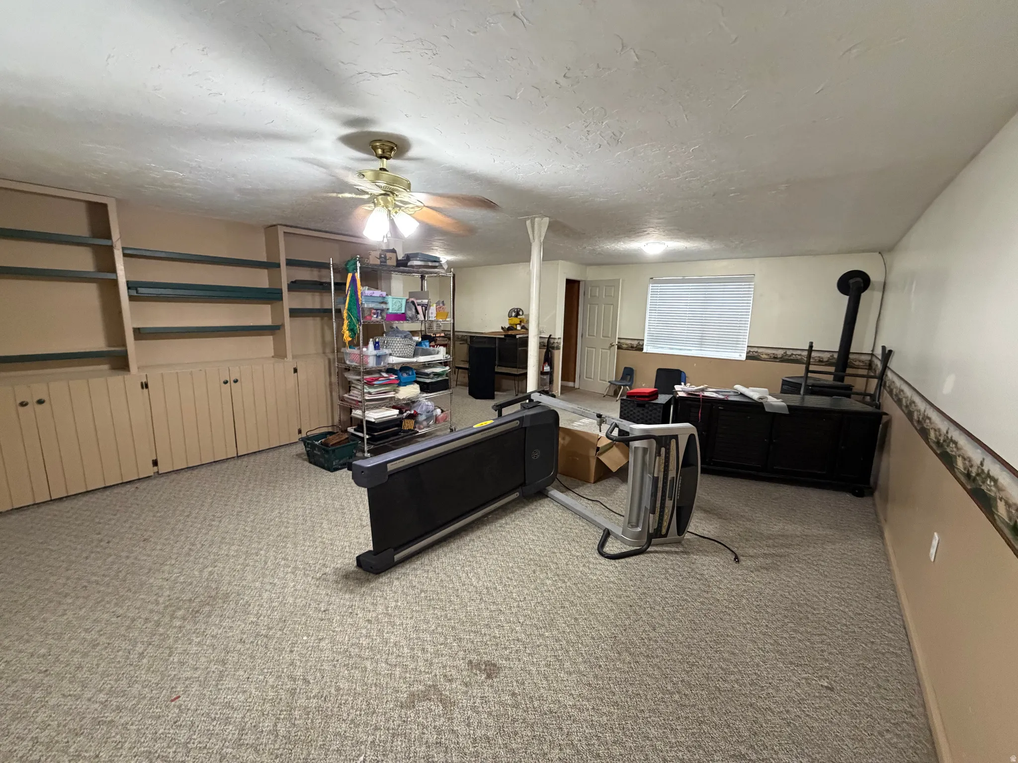 Spacious room featuring extensive built-in shelving and cabinetry, recessed lighting, and light-toned carpet flooring