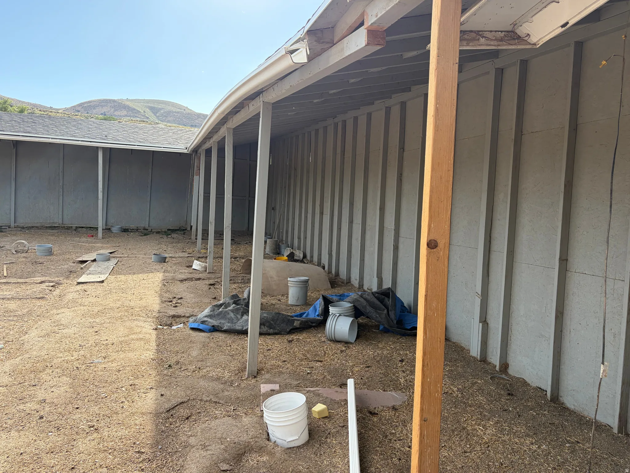 Expansive outdoor area featuring a covered patio structure and a granular ground surface