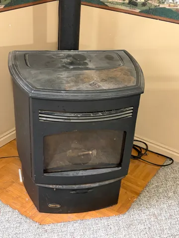 Freestanding black pellet stove with a glass-fronted firebox and a black stovepipe
