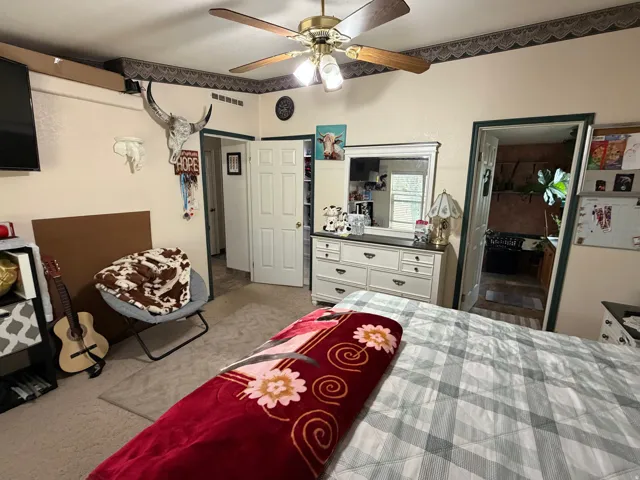 Master bedroom featuring a ceiling fan with integrated lighting, a wall-mounted television, and walk in closet