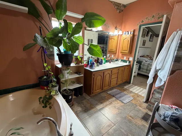Master Bathroom featuring a built-in tub, dual sink vanity with wood cabinetry, and a mirrored medicine cabinet, Tile flooring and seperate shower