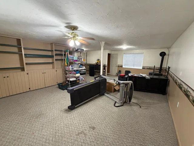 Spacious room featuring extensive built-in shelving and cabinetry, recessed lighting, and light-toned carpet flooring