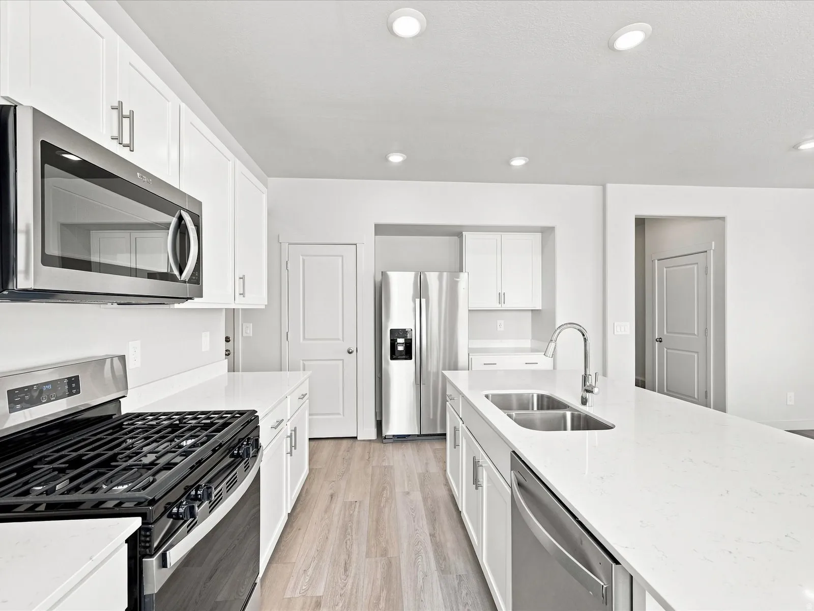 Modern kitchen featuring white cabinetry, stainless steel appliances, light wood-finish flooring, recessed lighting, and white countertops