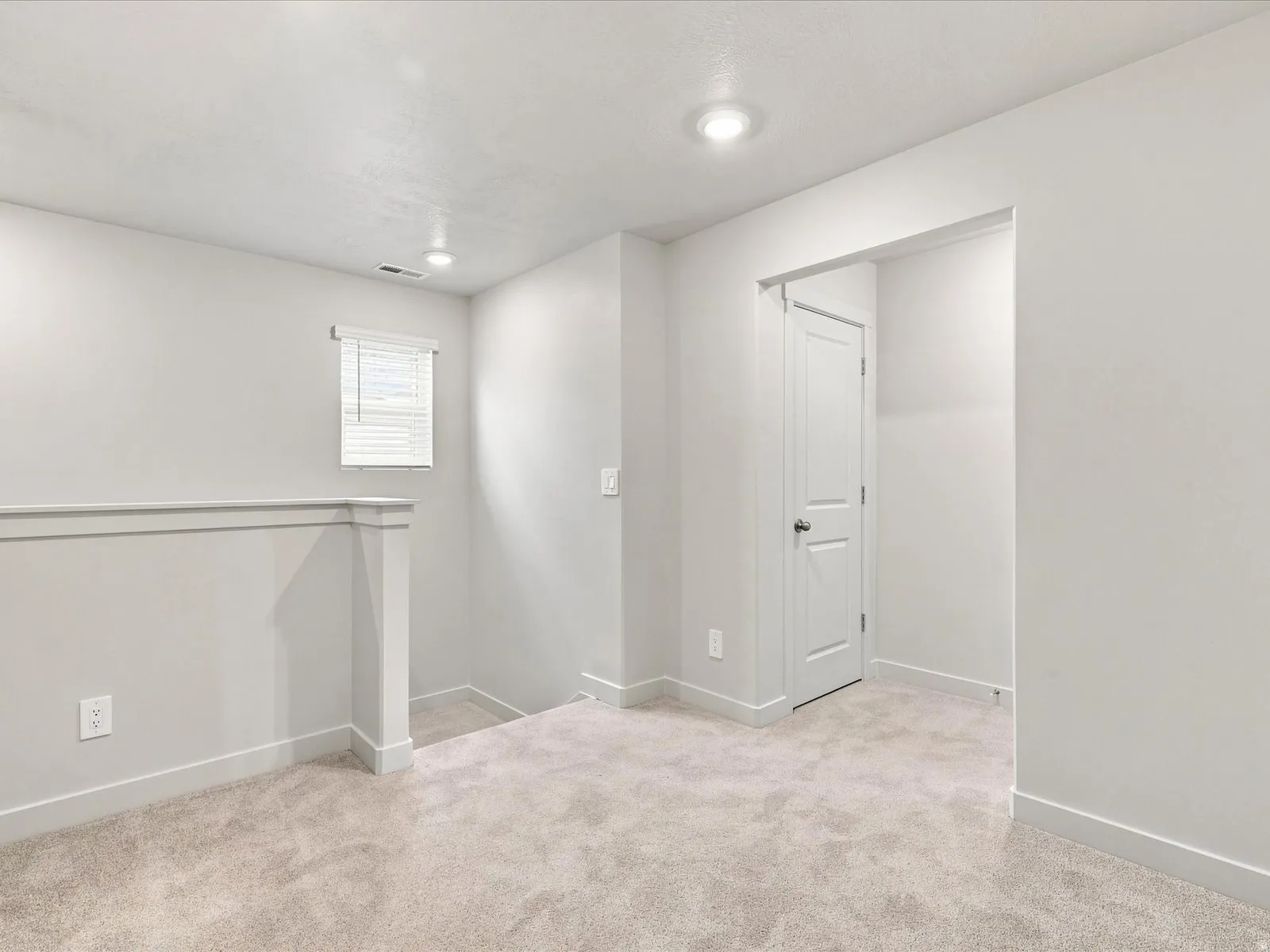 Plush carpeting throughout, featuring recessed lighting, a white paneled interior door, and a window with blinds
