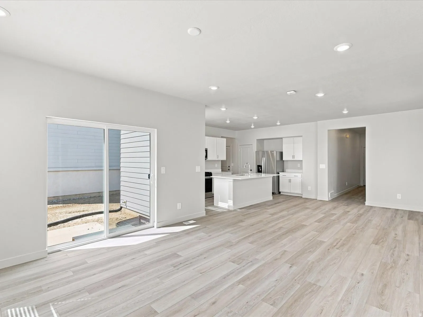 Open-concept living area with wood-finish flooring, recessed lighting, and a sliding glass door