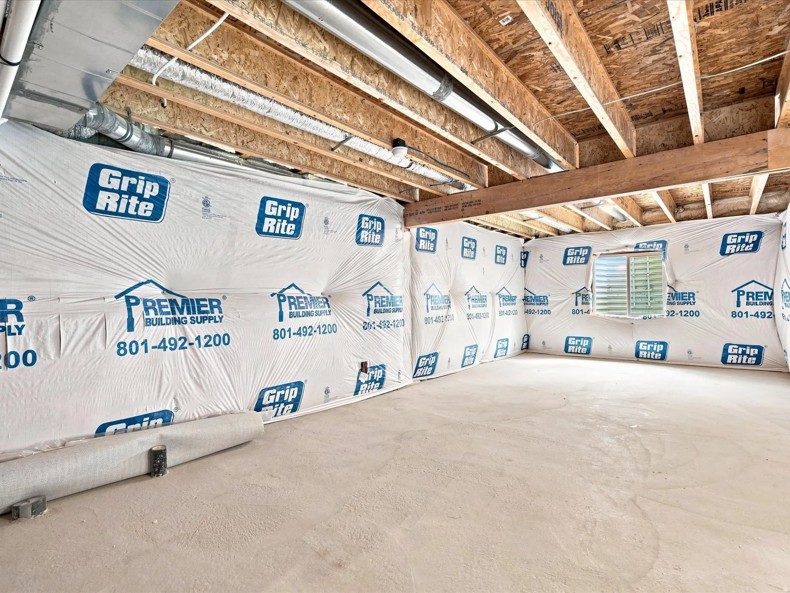 Unfinished basement with exposed ceiling joists, concrete flooring, and a single window