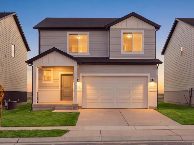 Modern two-story residence featuring light gray siding, an attached two-car garage, a covered front porch, and a concrete driveway