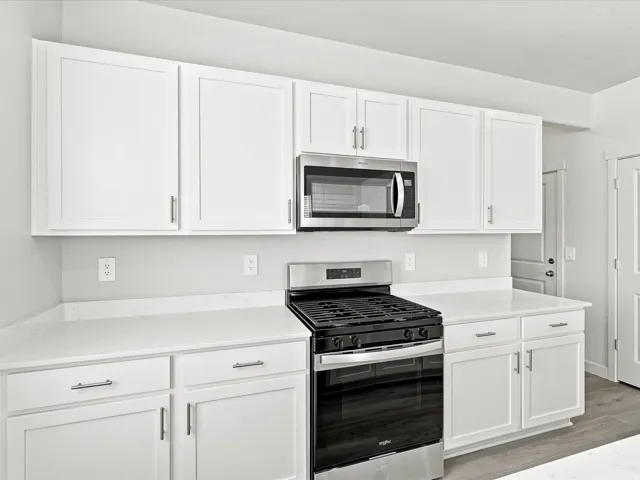White shaker cabinetry, stainless steel microwave, gas range, and light-toned countertops