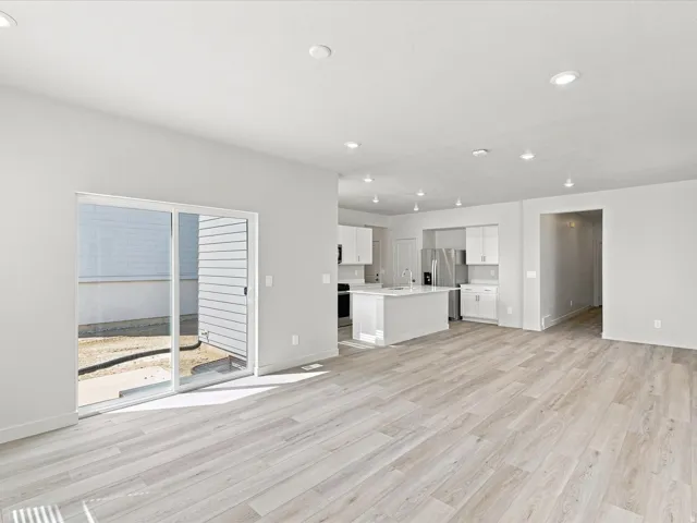 Open-concept living area with wood-finish flooring, recessed lighting, and a sliding glass door