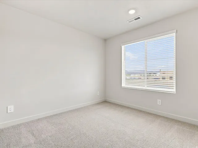 Recessed ceiling lighting, large window with blinds, light-toned carpet flooring, neutral wall paint, and white trim