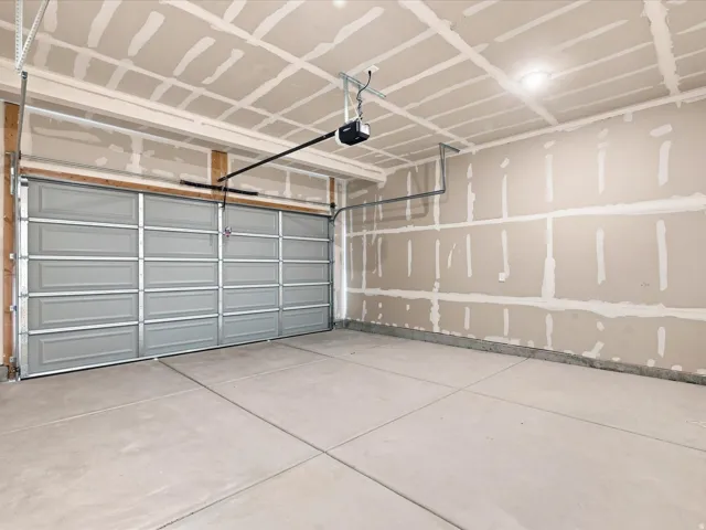 Concrete flooring, drywall walls, and a paneled garage door with an automatic opener
