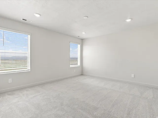 Recessed lighting, two windows with blinds, gray carpeting, and neutral wall tones