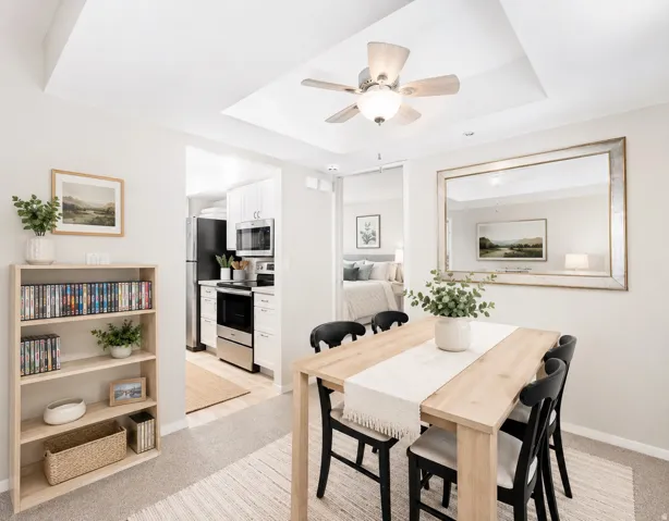 Dining area featuring a tray ceiling with a ceiling fan, light wood-finish dining table, and carpeted flooring