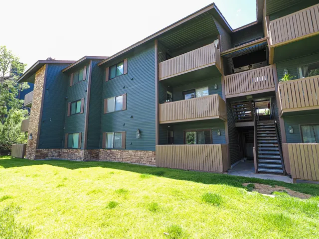 Multi-story building featuring dark green siding and stone veneer accents
