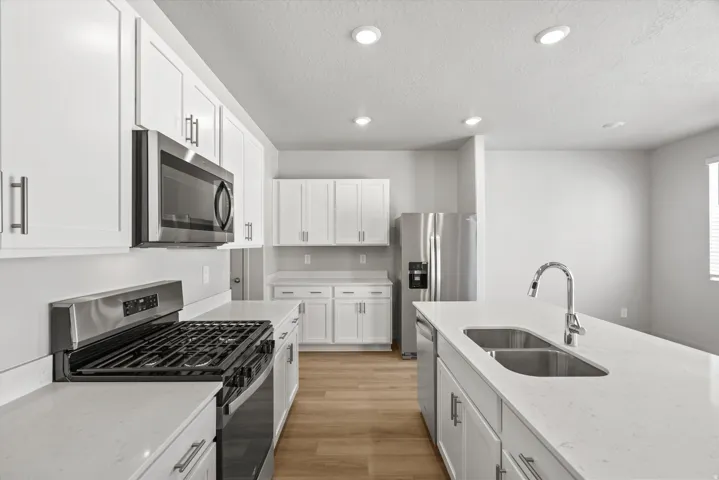 Modern kitchen featuring white cabinetry, stainless steel appliances, and light wood-finish flooring